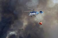 A firefighter helicopter flies over a wildfire in Benitatxell near Alicante, Spain September 5, 2016. REUTERS/Heino Kalis