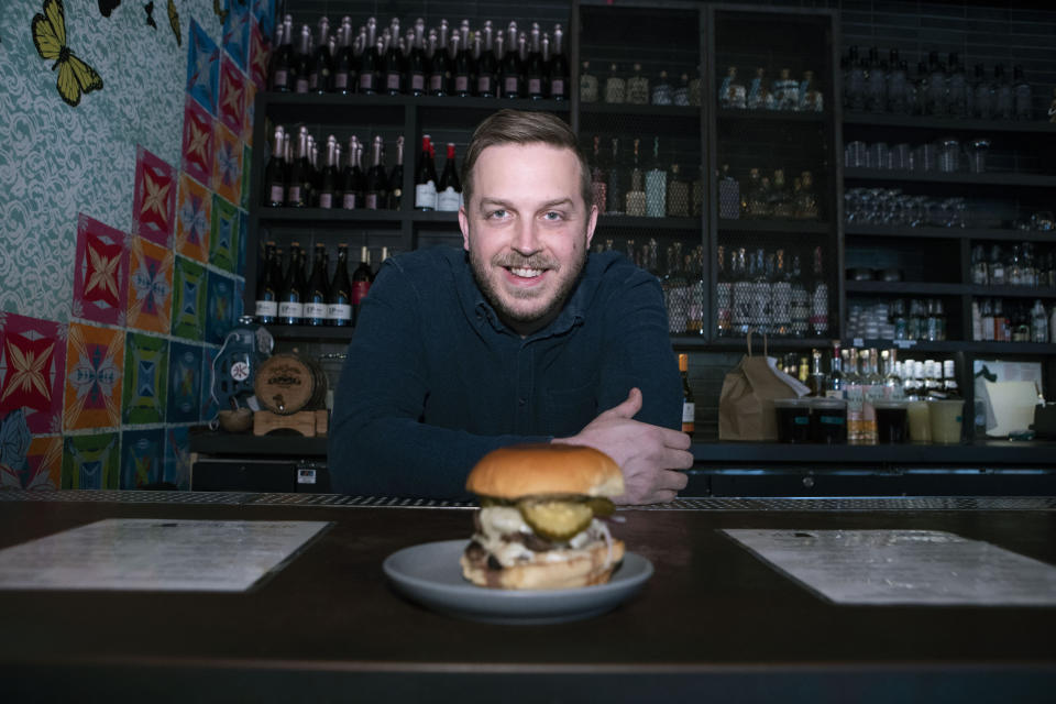 Josh Phillips, the co-owner of Espita, a stylish Mexican restaurant, displays a Ghostburger at his restaurant in downtown Washington, Monday, Feb. 15, 2021. Phillips opened a delivery-only brand called Ghostburger in August to keep Espita’s kitchen running through the winter. He chose burgers because he wanted to reach new customers at a lower price point than Espita. It’s been so successful that Phillips is now scouting for locations for standalone Ghostburger restaurants. (AP Photo/Jose Luis Magana)