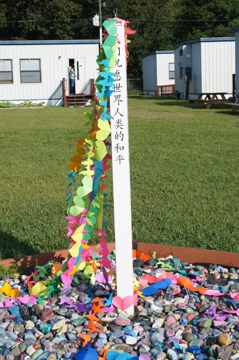 A "Peace Pole" is an iconic item on many Montessori campuses. In the background are some of the "cottages" that serve as school buildings at Coastal Empire Montessori School.