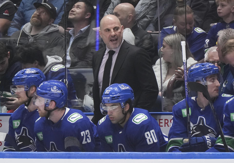Vancouver Canucks coach Rick Tocchet stands on the bench behind Elias Pettersson, Elias Lindholm, Arshdeep Bains and Ilya Mikheyev, from left, during the first period of the team's NHL hockey game against the Pittsburgh Penguins on Tuesday, Feb. 27, 2024, in Vancouver, British Columbia. (Darryl Dyck/The Canadian Press via AP)