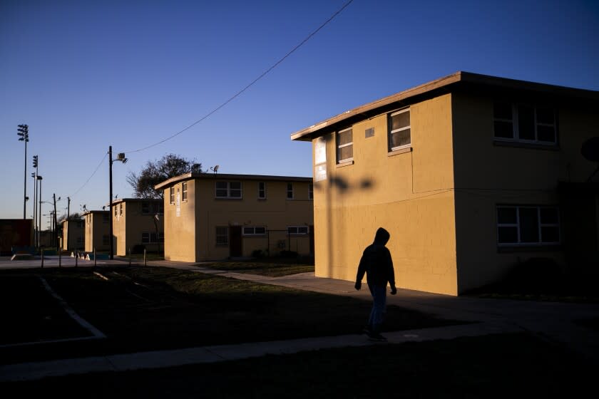 Watts, CA - December 17: A resident is silhouetted walking through Nickerson Gardens, the largest public housing development west of the Mississippi River in Watts at sunset Friday, Dec. 17, 2021. (Allen J. Schaben / Los Angeles Times)