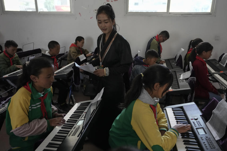 A teacher watches students practice on electronic pianos at the Shangri-La Key Boarding School during a media-organized tour in Dabpa county, Kardze Prefecture, Sichuan province, China on Sept. 5, 2023. (AP Photo/Andy Wong)