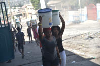 <p>Women carry buckets of water on a barricaded street in central Port-au-Prince, July 9, 2018, following two days of deadly looting and arson triggered by a quickly-aborted government attempt to raise fuel prices. (Photo: Hector Retamal/AFP/Getty Images) </p>