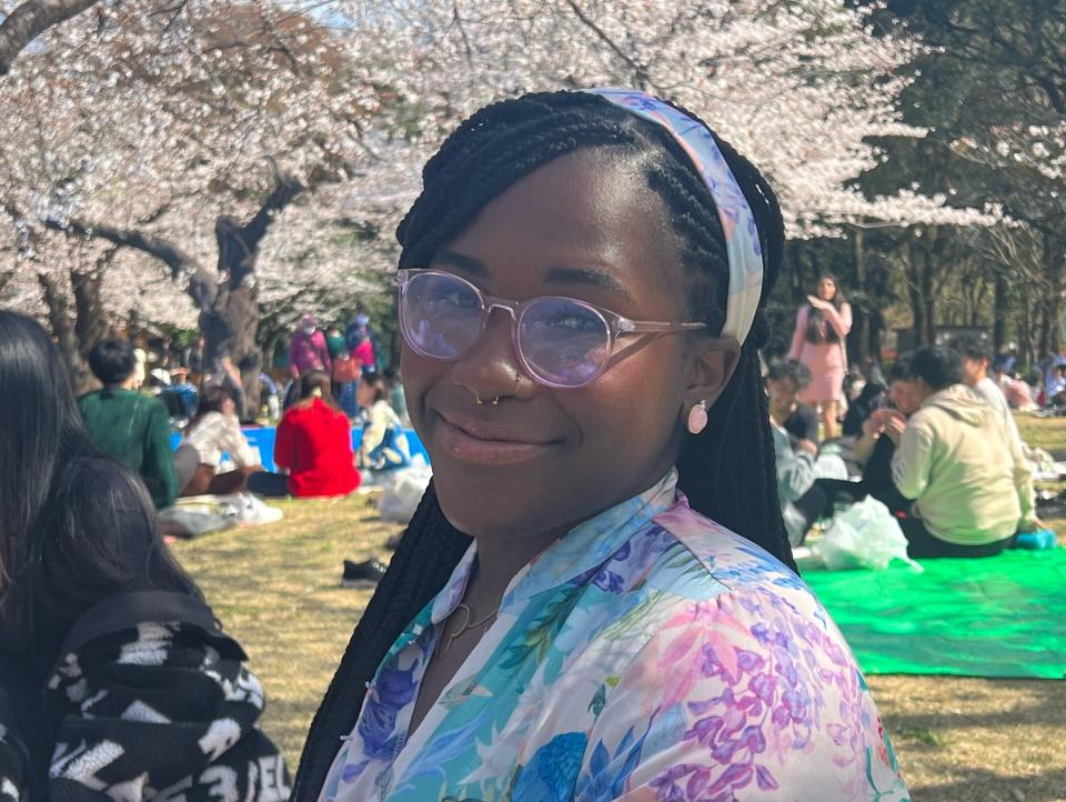 Renee Marant smiling in front of cherry-blossom trees.