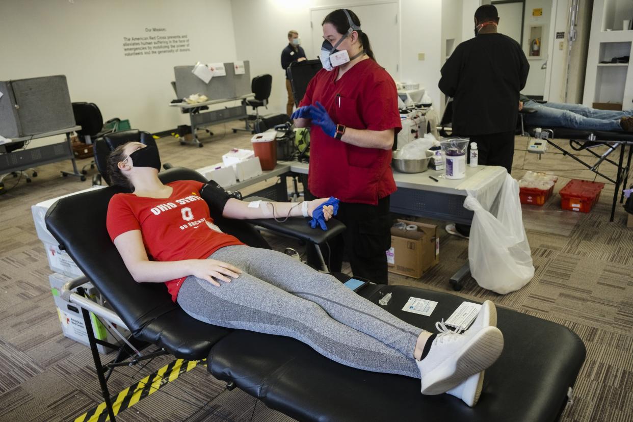 Olivia Howard, left, of Columbus, leans back as Travis McPherson, center, a specialist with the American Red Cross, chats with her after starting her blood donation on Friday, Jan. 22, 2021 at the American Red Cross in Columbus, Ohio. By giving blood, some patients are able to see quick insights to their health, and as the COVID-19 pandemic continues, whether or not they have antibodies.