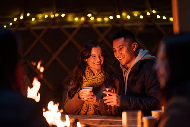 Love Ignites Beside the Crackle of a Fire Pit. Amidst a world ablaze with warmth, a couple's quietude is illuminated by the tender dance of flames, as they savor a tranquil evening together