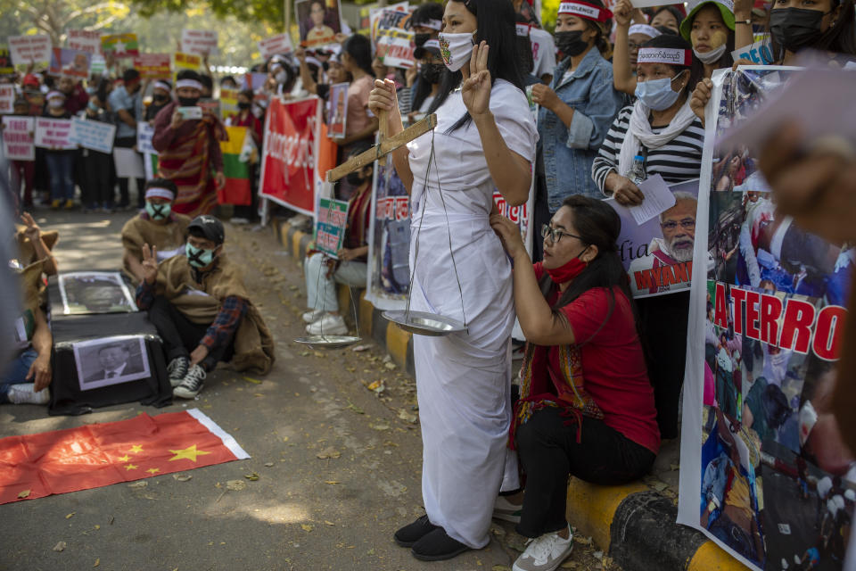 A Chin refugee from Myanmar adjusts the dress of another refugee dressed as lady justice during a protest against military coup in Myanmar, in New Delhi, India, Wednesday, March 3, 2021. (AP Photo/Altaf Qadri)