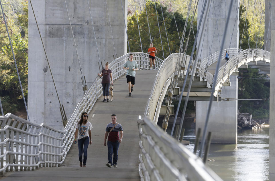 This Oct. 1, 2013 photo shows runners and pedestrians along a bridge suspended under the Lee Bridge over the James river from Belle Isle, in Richmond, Va., where you’ll find locals exploring the 54-acre island and resting on its rocky shores. Belle Isle was first explored in 1607 by Capt. John Smith, who helped establish England’s first North American settlement in Virginia. (AP Photo/Steve Helber)