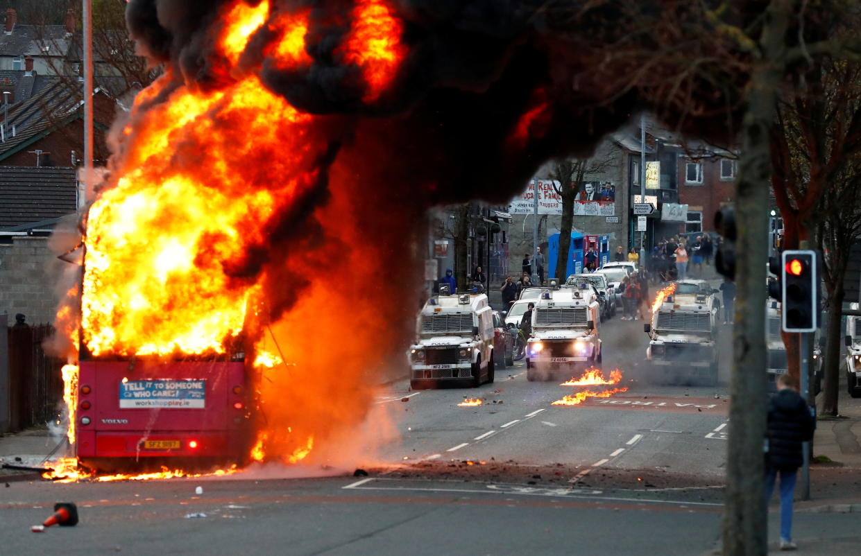 Police vehicles are seen behind a hijacked bus burning on Shankill Road as protests continue in Belfast, Northern Ireland, April 7, 2021. REUTERS/Jason Cairnduff     TPX IMAGES OF THE DAY