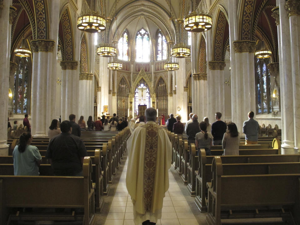 Rev. Msgr. Kevin O'Neill walks down the aisle of the Cathedral of St. Helena to begin mass in Helena, Mont., Sunday, April 26, 2020. The Roman Catholic cathedral was one of the churches across Montana to resume services on Sunday with reduced capacity and enforced social distancing as part of the state's first phase of easing coronavirus restrictions. (AP Photo/Matt Volz)