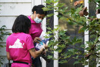 In this Saturday, Oct. 16, 2021, photo Han Jones, right, and Lucy Hartman, of Planned Parenthood Advocates of Virginia leave literature as they knock on doors while canvassing the area to encourage voters to vote in Richmond, Va. (AP Photo/Steve Helber)