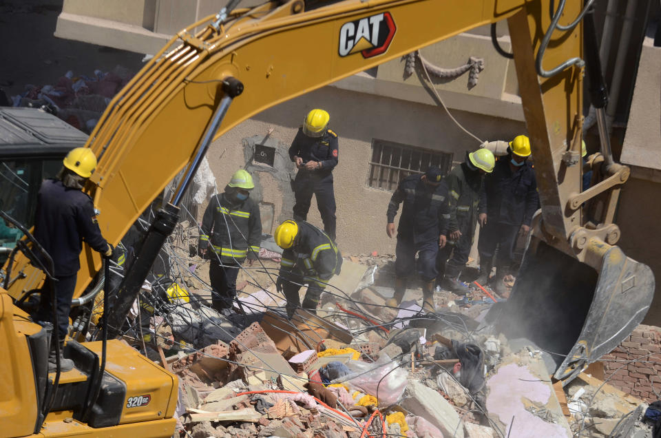 Rescuers look for victims on the rubble of a collapsed apartment building in the el-Salam neighborhood, in Cairo, Egypt, Saturday, March 27, 2021. A nine-story apartment building collapsed in the Egyptian capital early Saturday, killing at several and injuring about two dozen others, an official said. (AP Photo/Tarek wajeh)