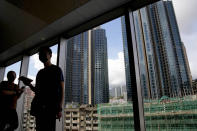 People stand in front of the Grand Central residential building complex where a HK$10.8 million (US$1.4 million) 449 square feet single-room unit will be offered as a prize in a lucky draw, in Hong Kong. Coronavirus vaccine incentives offered by Hong Kong companies, including a lucky draw for an apartment, a Tesla car and even gold bars, are helping boost the city’s sluggish inoculation rate. (AP Photo/Kin Cheung)