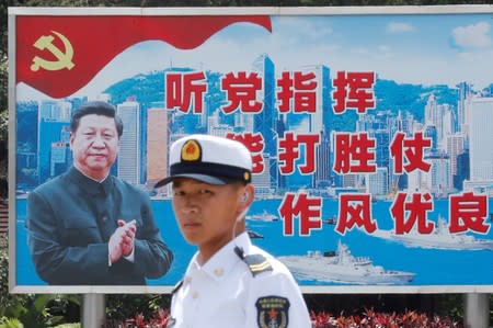 FILE PHOTO: A People's Liberation Army Navy soldier stands in front of a backdrop featuring Chinese President Xi Jinping during an open day of Stonecutters Island naval base, in Hong Kong