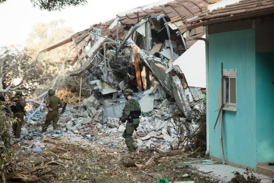 Israeli soldiers walk near houses that were destroyed in Be'eri, Israel.