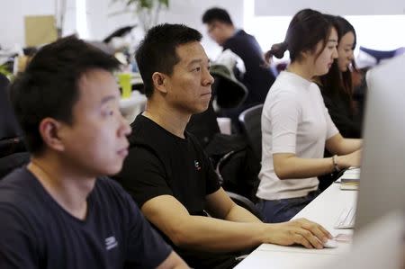 Jia Yueting, co-founder and head of Le Holdings Co Ltd, also known as LeEco and formerly as LeTV, uses a computer on a staff's seat as he poses for a photo after a Reuters interview at LeEco headquarters in Beijing, China, picture taken April 22, 2016. REUTERS/Jason Lee