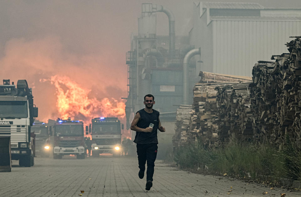 ALBERGARIA A VELHA, PORTUGAL - JULY 13: A worker runs away when a forest fire that has hit the lumber factory where he works on July 13, 2022 in Albergaria a Velha, Portugal. Wildfires have swept across the central part of the country amid temperatures exceeding 40 degrees celsius. (Photo by Octavio Passos/Getty Images)