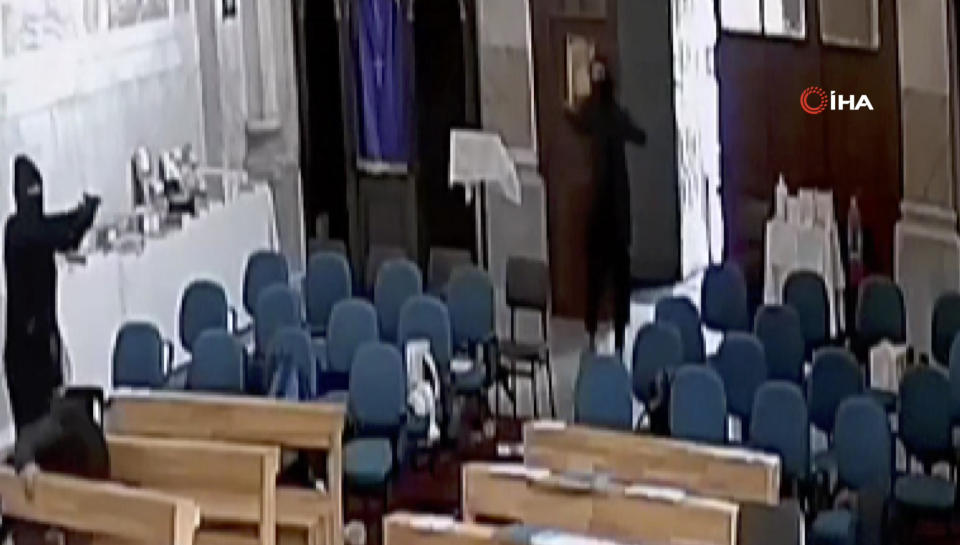 A screenshoot from video footage taken from a CCTV camera, shows two masked men holding guns inside Santa Maria church in Istanbul, Turkey, Sunday, Jan. 28, 2024. Two masked assailants attacked a church in Istanbul during Sunday services, killing one person, Turkish officials said. (IHA via AP)