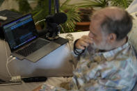 Michael Bommer, who is terminally ill with colon cancer, listens to his AI generated voice during a meeting with The Associated Press at his home in Berlin, Germany, Wednesday, May 22, 2024. Bommer, who has only a few more weeks to live, teamed up with friend who runs the AI-powered legacy platform Eternos to "create a comprehensive, interactive AI version of himself, allowing relatives to engage with his life experiences and insights," after he has passed away. (AP Photo/Markus Schreiber)