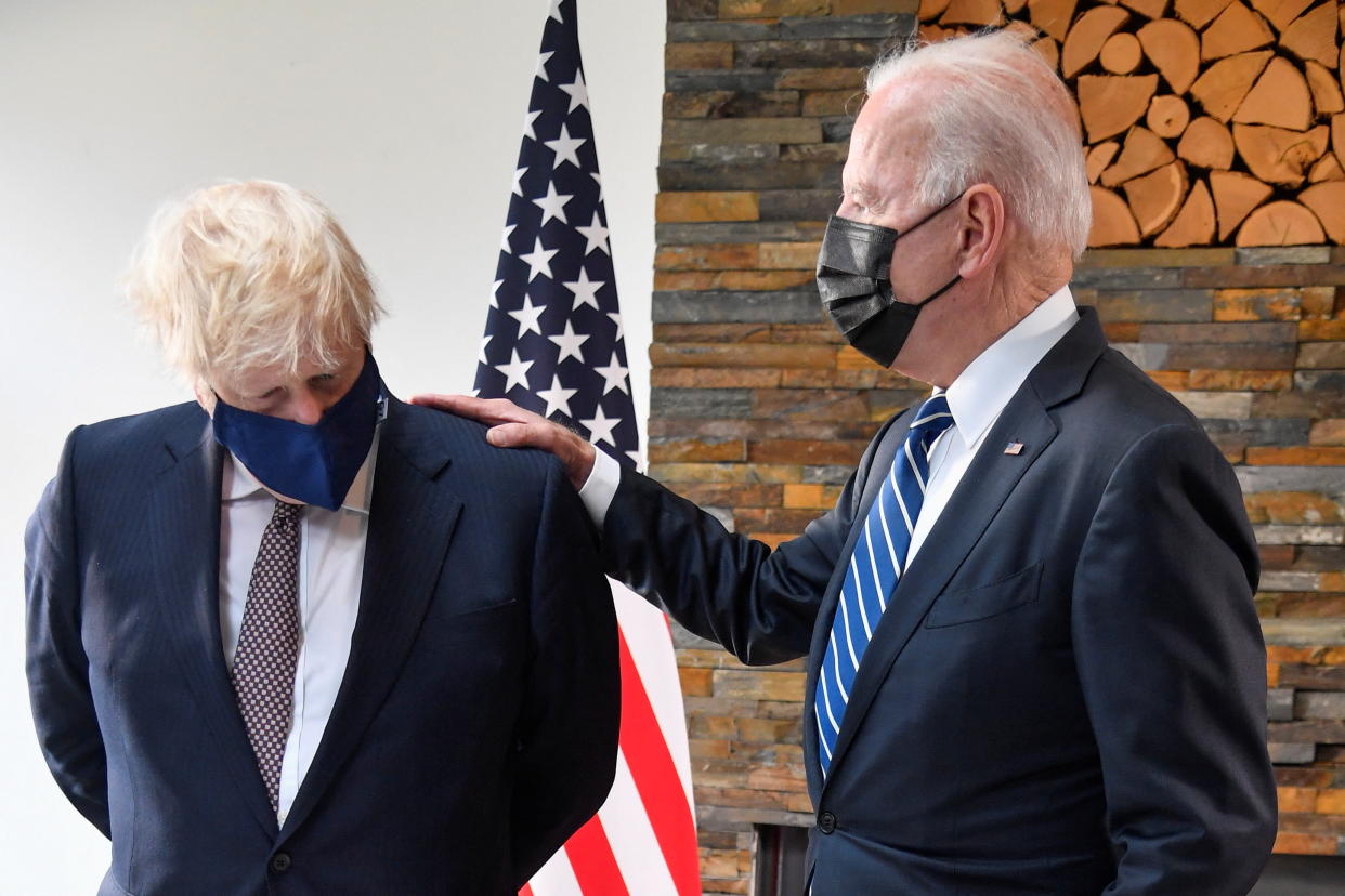TOPSHOT - Britain's Prime Minister Boris Johnson (L) and US President Joe Biden, wearing face coverings due to Covid-19, view documents relating to the Atlantic Charter prior to a bi-lateral meeting at Carbis Bay, Cornwall on June 10, 2021, ahead of the three-day G7 summit being held from 11-13 June. - G7 leaders from Canada, France, Germany, Italy, Japan, the UK and the United States meet this weekend for the first time in nearly two years, for the three-day talks in Carbis Bay, Cornwall. (Photo by TOBY MELVILLE / POOL / AFP) (Photo by TOBY MELVILLE/POOL/AFP via Getty Images)