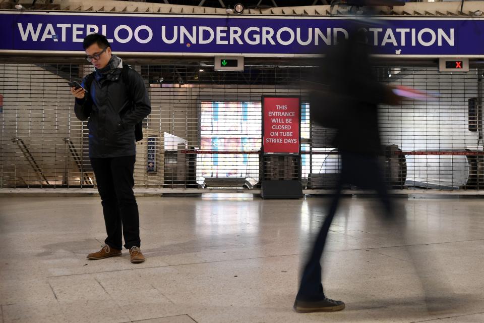 A man looks at his mobile phone at a barriered entrance to a tube station in Waterloo station
