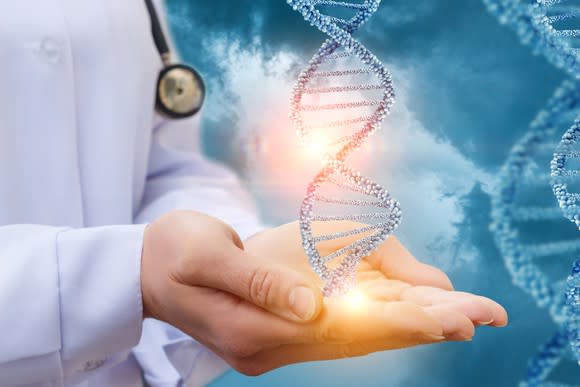 Double helix of DNA floating over the hands of a doctor