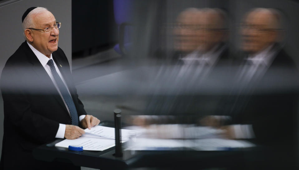 This photo taken with reflections in windows at the visitors tribune, Israel's President Reuven Rivlin delivers his speech during a special meeting of the German Parliament Bundestag commemorating the victims of the Holocaust in Berlin, Germany, Wednesday, Jan. 29, 2020. (AP Photo/Markus Schreiber)