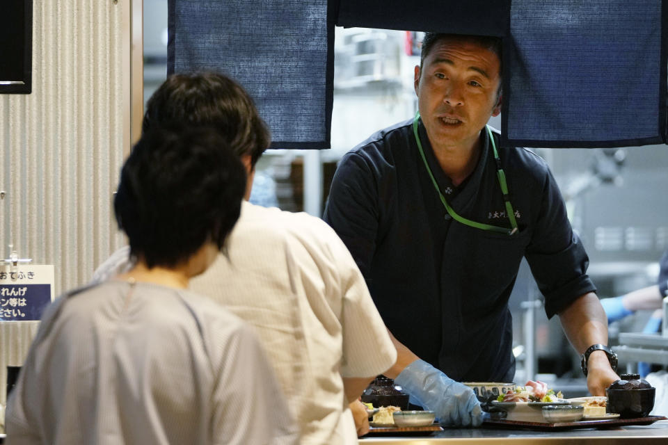 Katsumasa Okawa, owner of a fish store and a restaurant, serves meals he cooked to his customers at his restaurant in Iwaki, northeastern Japan, Thursday, July 13, 2023. Okawa said those tanks containing contaminated water at the damaged Fukushima nuclear power plant bothers him more than the treated water release into the sea. He wants to have them removed as soon as possible, especially after seeing "immense" tanks occupying much of the plant complex during his visit a few years ago. (AP Photo/Hiro Komae)