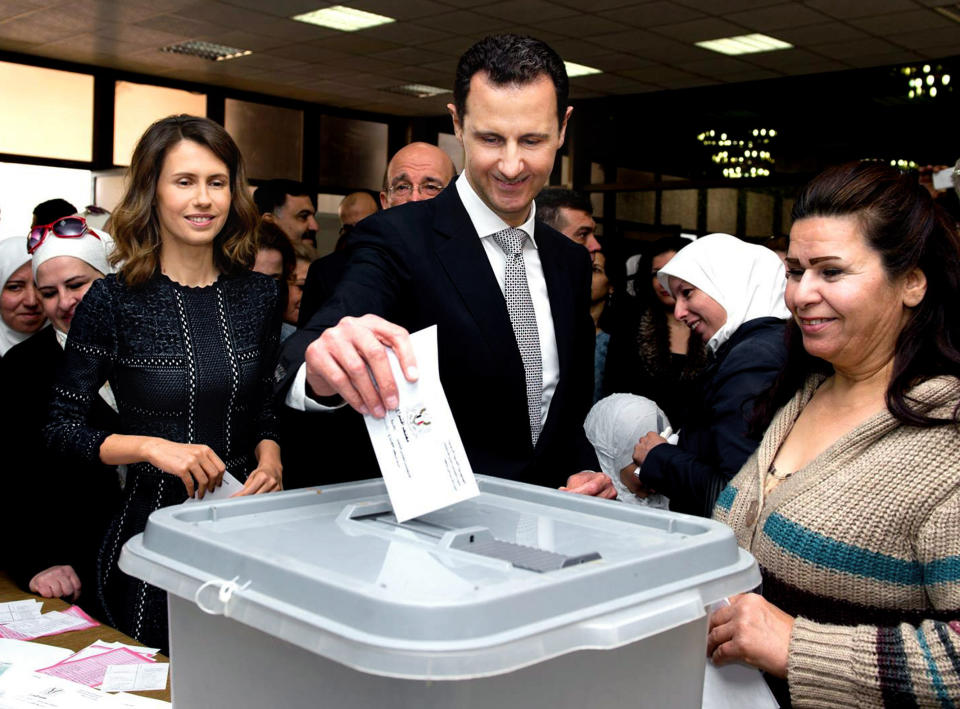 FILE - This April 13, 2016 file photo released on the official Facebook page of Syrian Presidency, shows Syrian President Bashar Assad casting his ballot in the parliamentary elections, as his wife Asma, left, stands next to him, in Damascus, Syria. The office of Syrian President Bashar Assad said Monday, March 8, 2021 that Assad and his wife have tested positive for the coronavirus and are both doing well. In a statement, Assad’s office said the first couple did PCR tests after they felt minor symptoms consistent with the COVID-19 illness. (Syrian Presidency via AP, File)