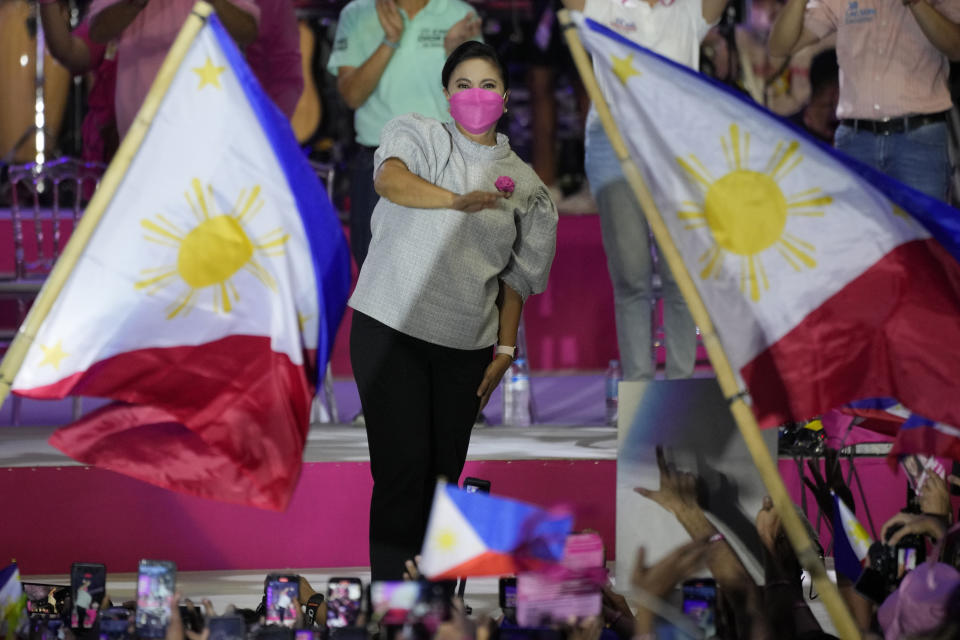 Presidential candidate, current Vice President Leni Robredo greets supporters as a Philippine flag is waved during a campaign rally that coincides with her birthday in Pasay City, Philippines on April 24, 2022. The winner of May 9, Monday's vote will inherit a sagging economy, poverty and deep divisions, as well as calls to prosecute outgoing leader Rodrigo Duterte for thousands of deaths as part of a crackdown on illegal drugs. (AP Photo/Aaron Favila)