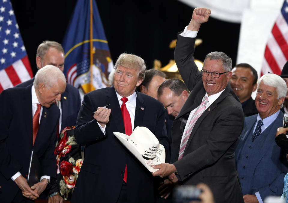 FILE - In this Dec. 4, 2017, file photo, President Donald Trump signs the hat of Bruce Adams, chairman of the San Juan County Commission, after signing a proclamation to shrink the size of Bears Ears and Grand Staircase Escalante national monuments, in Salt Lake City. The selections for the 15-person Bears Ears National Monument panel posted online Friday, April 19, 2019 by the U.S. Bureau of Land Management reveal a few people who seem to strike a middle ground, but nobody who was an outspoken proponent of the monument created by President Barack Obama in December 2016. (AP Photo/Rick Bowmer, File)