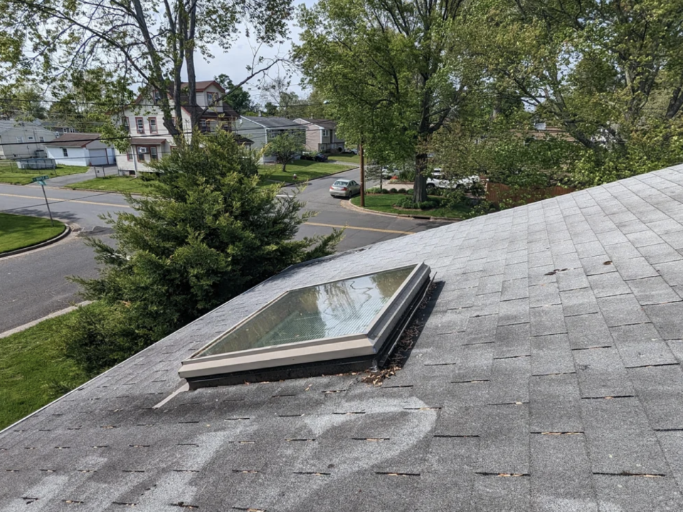 Skylight on a house roof with surrounding trees, viewed from an upper window