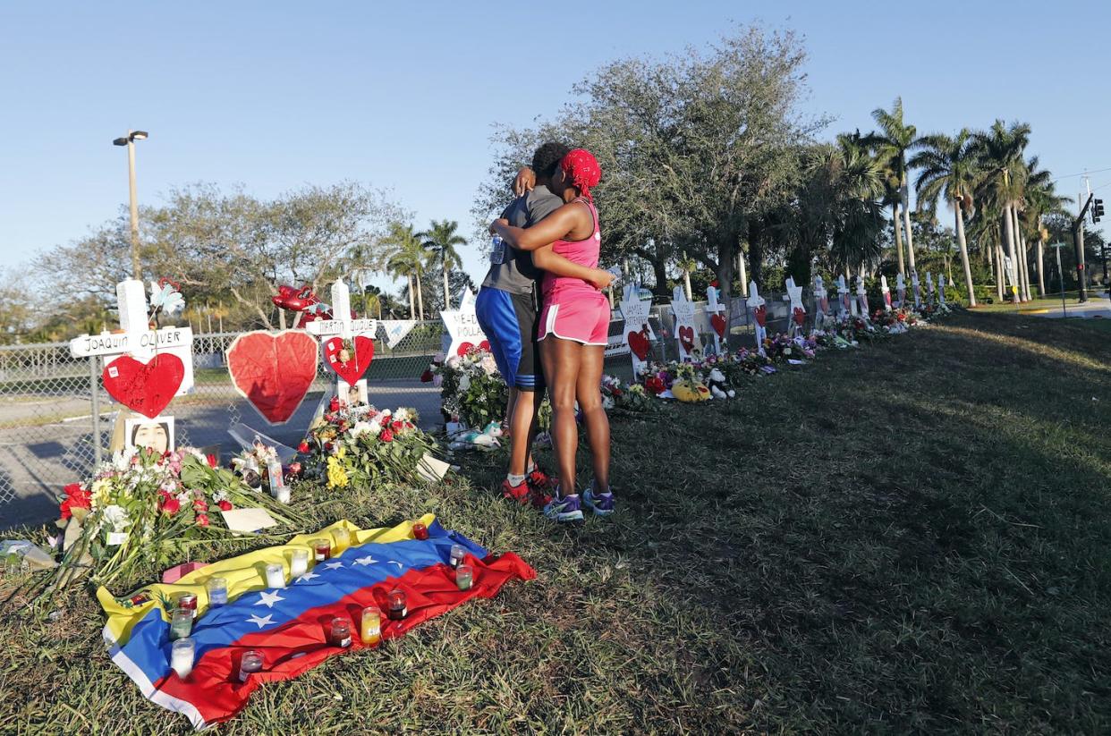 Two mourners embrace at a memorial for those killed in the Parkland, Florida, school shooting in 2018. <a href="https://newsroom.ap.org/detail/SchoolShootingFlorida/19d9b3109dad473aa598fc9382c2c1ee/photo" rel="nofollow noopener" target="_blank" data-ylk="slk:AP Photo/Gerald Herbert;elm:context_link;itc:0;sec:content-canvas" class="link ">AP Photo/Gerald Herbert</a>