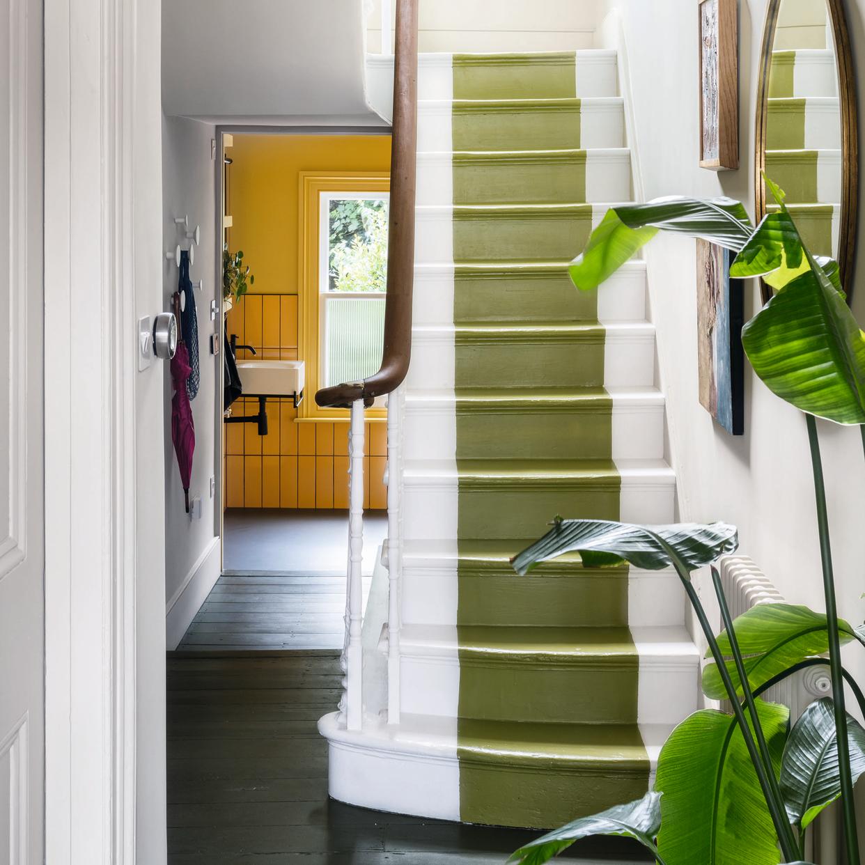  Hallway with green stair runner on painted white stairs. 