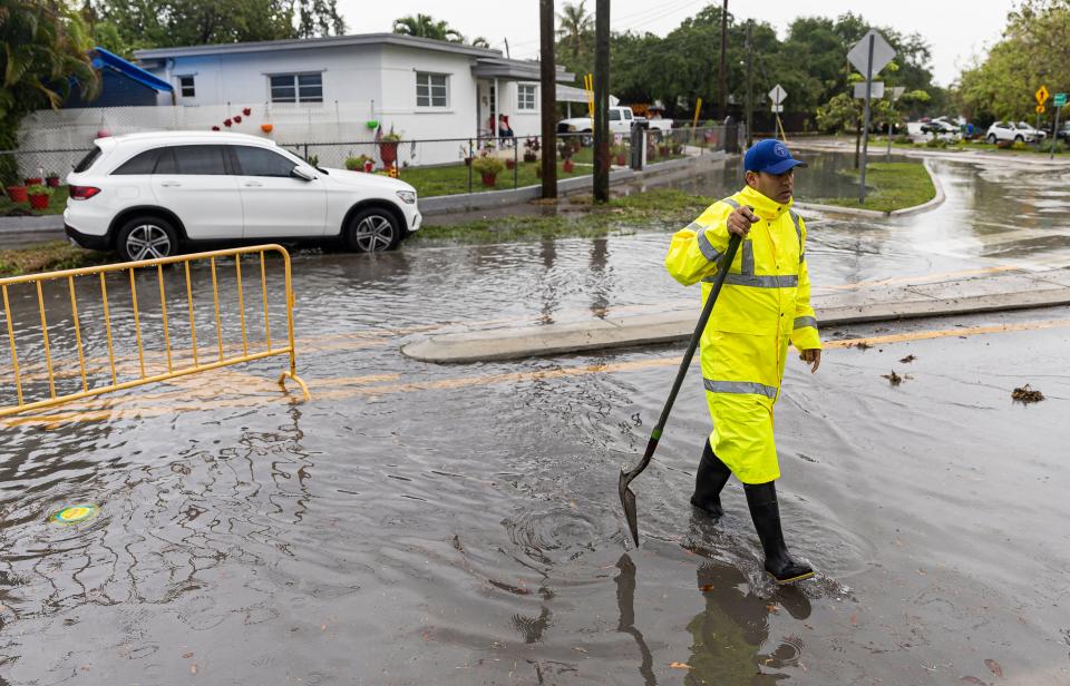 City of Miami Community Response Team Member Eddy Hernandez uses a shovel to scoop debris from a drain following heavy rain at the Bay of Pigs Memorial Park on Wednesday, April 12, 2023, in Miami, Fla. (Matias J. Ocner/Miami Herald via AP)