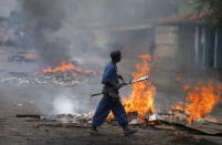 A policeman walks in front of a burning barricade during a protest against Burundi's President Pierre Nkurunziza and his bid for a third term in Bujumbura, Burundi, May 22, 2015. REUTERS/Goran Tomasevic