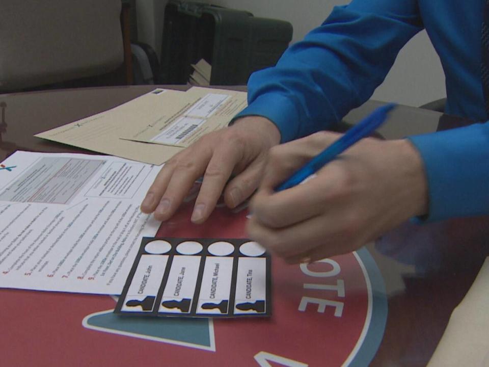 An election worker demonstrates voting with a sample ballot. Voters in the upcoming Tu Nedhé-Wiilideh byelection will receive their ballots by mail.  (Kaicheng Xin/CBC - image credit)