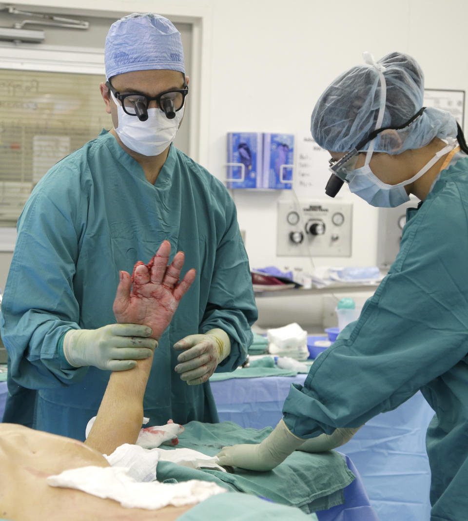 Los médicos examinan la mano después de la cirugía. (AP Photo/Pat Sullivan)