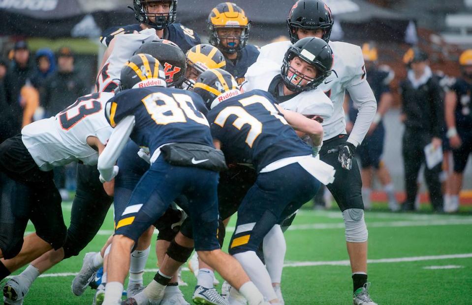 Kennewick senior running back Myles Mayovsky is wrapped up by Bellevue defenders Cal Zimmerman and Colin Miller during Saturday afternoon’s 3A football state championship game at Sparks Stadium in Puyallup, Washington, on Dec. 4, 2021. Bellevue won the title, 17-13.