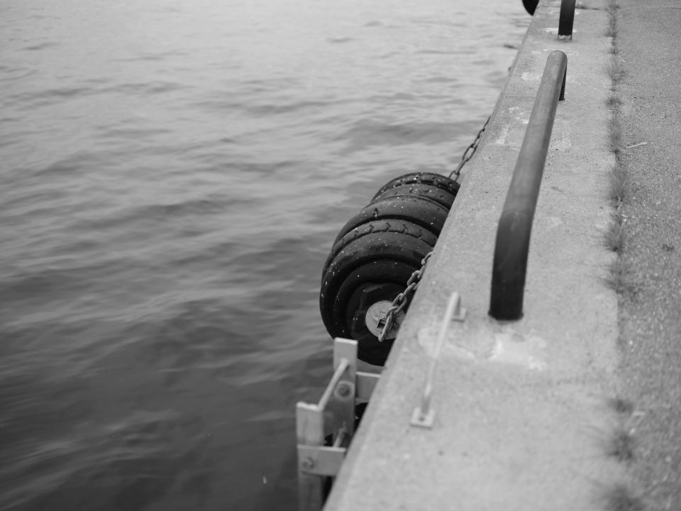 Black and white photo of tires on a marina wall