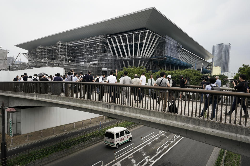 FILE - In this July 3, 2019, file photo, members of the media gather outside the Tokyo Aquatics Center, a venue for swimming and diving at the Tokyo 2020 Summer Olympics in Tokyo. The Olympics will be simply a sideshow for some Tokyo visitors, astounded by the cleanliness, courtesy and order. Japan’s sprawling capital is a dense mix of the traditional and eccentric where bowing meets bustle. (AP Photo/Jae C. Hong, File)