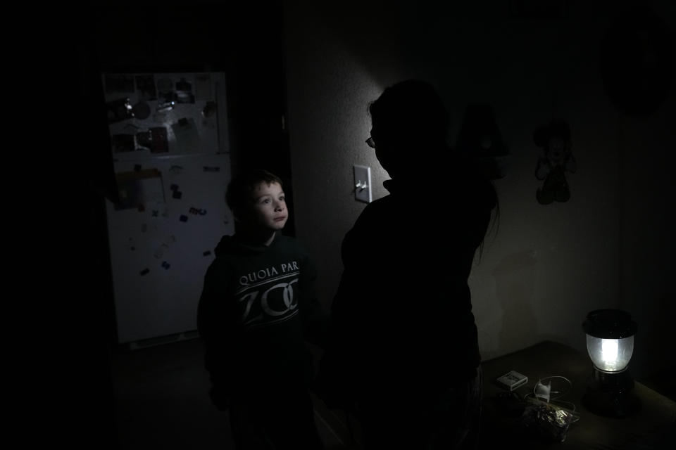 Timmy Ramirez, left, looks up to his mother's friend, Bunny Bailey, as they walk through Bailey's apartment after an earthquake in Rio Dell, Calif., Tuesday, Dec. 20, 2022. A strong earthquake shook a rural stretch of Northern California early Tuesday, jolting residents awake, cutting off power to thousands of people, and damaging some buildings and a roadway, officials said. (AP Photo/Godofredo A. Vásquez)