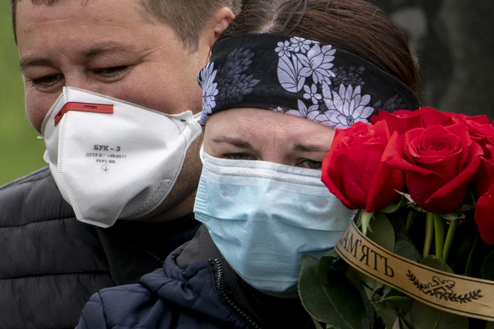 In this photo taken on Saturday, May 2, 2020, Nadiya, right, and Andrii Muchka, daughter and son of Semen Muchka, 71, who died of coronavirus disease, wear face masks during his funeral at a cemetery in Krynytsya, Ukraine. Ukraine's troubled health care system has been overwhelmed by COVID-19, even though it has reported a relatively low number of cases. (AP Photo/Evgeniy Maloletka)