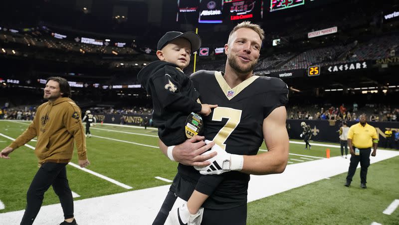 New Orleans Saints quarterback Taysom Hill (7) holds his son Beau before an NFL football game against the Chicago Bears in New Orleans, Sunday, Nov. 5, 2023.