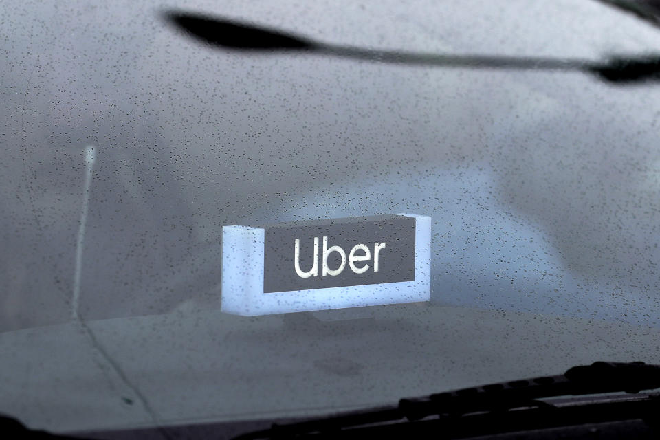 FILE - In this May 15, 2020 file photo, an Uber sign is displayed inside a car in Chicago. Uber finally got its food delivery company, acquiring Postmates in a $2.65 billion all-stock deal, the ride-hailing giant confirmed Monday, July 6. (AP Photo/Nam Y. Huh, File)