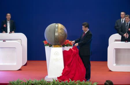 Chinese President Xi Jinping (C) unveils a sculpture during the opening ceremony of the Asian Infrastructure Investment Bank (AIIB) in Beijing, China, January 16, 2016. REUTERS/Mark Schiefelbein/Pool