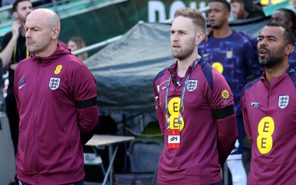 Lee Carsley (left) stands silent as his assistant coach Ashley Cole (right) sings the national anthem in Dublin