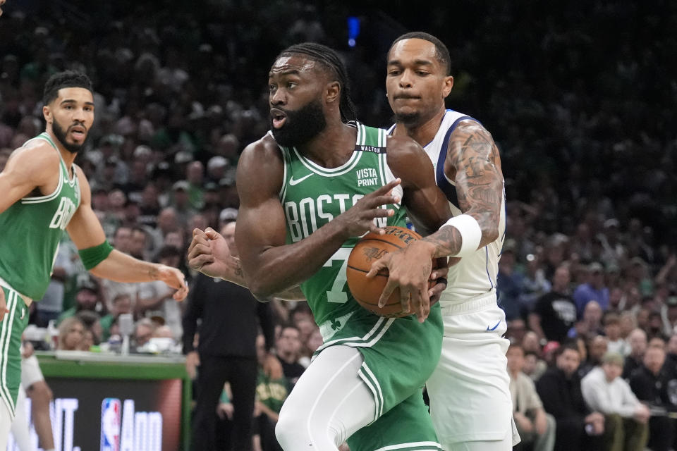 Boston Celtics guard Jaylen Brown, center, drives toward the basket as Dallas Mavericks forward P.J. Washington, right, defends and Celtics forward Jayson Tatum, left, watches during the first half of Game 5 of the NBA basketball finals, Monday, June 17, 2024, in Boston. (AP Photo/Charles Krupa)