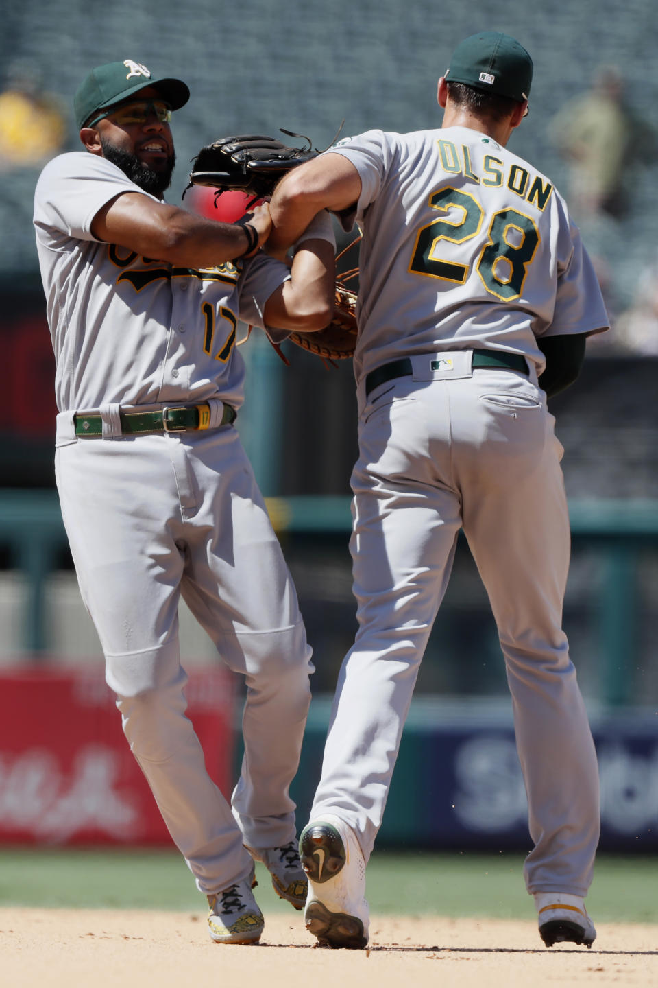 Oakland Athletics shortstop Elvis Andrus, left, wins the battle to catch a fly ball with first baseman Matt Olson hit by Los Angeles Angels' Kurt Suzuki during the sixth inning of a baseball game in Anaheim, Calif., Saturday, July 31, 2021. (AP Photo/Alex Gallardo)