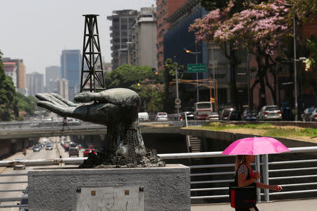 A woman walks past a sculpture outside a building of Venezuela's state oil company PDVSA in Caracas, Venezuela May 17, 2019. REUTERS/Ivan Alvarado